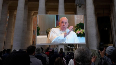 Papst Franziskus ist auf einem Monitor zu sehen, um die Gläubigen zu segnen, die sich auf dem Petersplatz versammelt haben. (Foto: Alessandra Tarantino/AP/dpa)