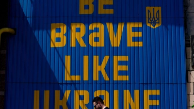 Ein Mann geht an einem Schild vorbei, auf dem „Be brave like Ukraine“ steht. (Foto: Jae C. Hong/AP/dpa)