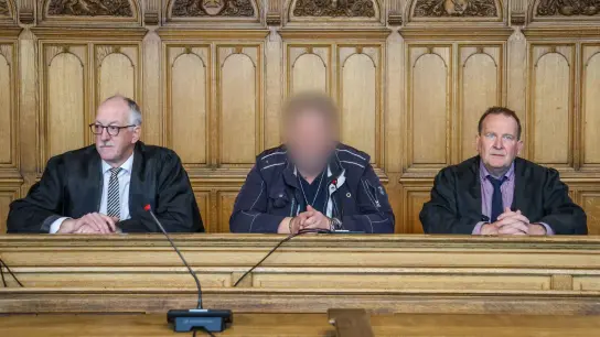Der Angeklagte (M) sitzt vor der Urteilsverkündung im Prozess wegen Mordes im Landgericht Bremen zwischen seinen Verteidigern. (Foto: Focke Strangmann/dpa)