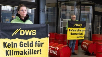 Mit roten Ölfässern protestieren Aktivisten von Greenpeace vor der Zentrale von DWS Investment in Frankfurt gegen die Investitionspolitik des Fonds. (Foto: Boris Roessler/dpa)