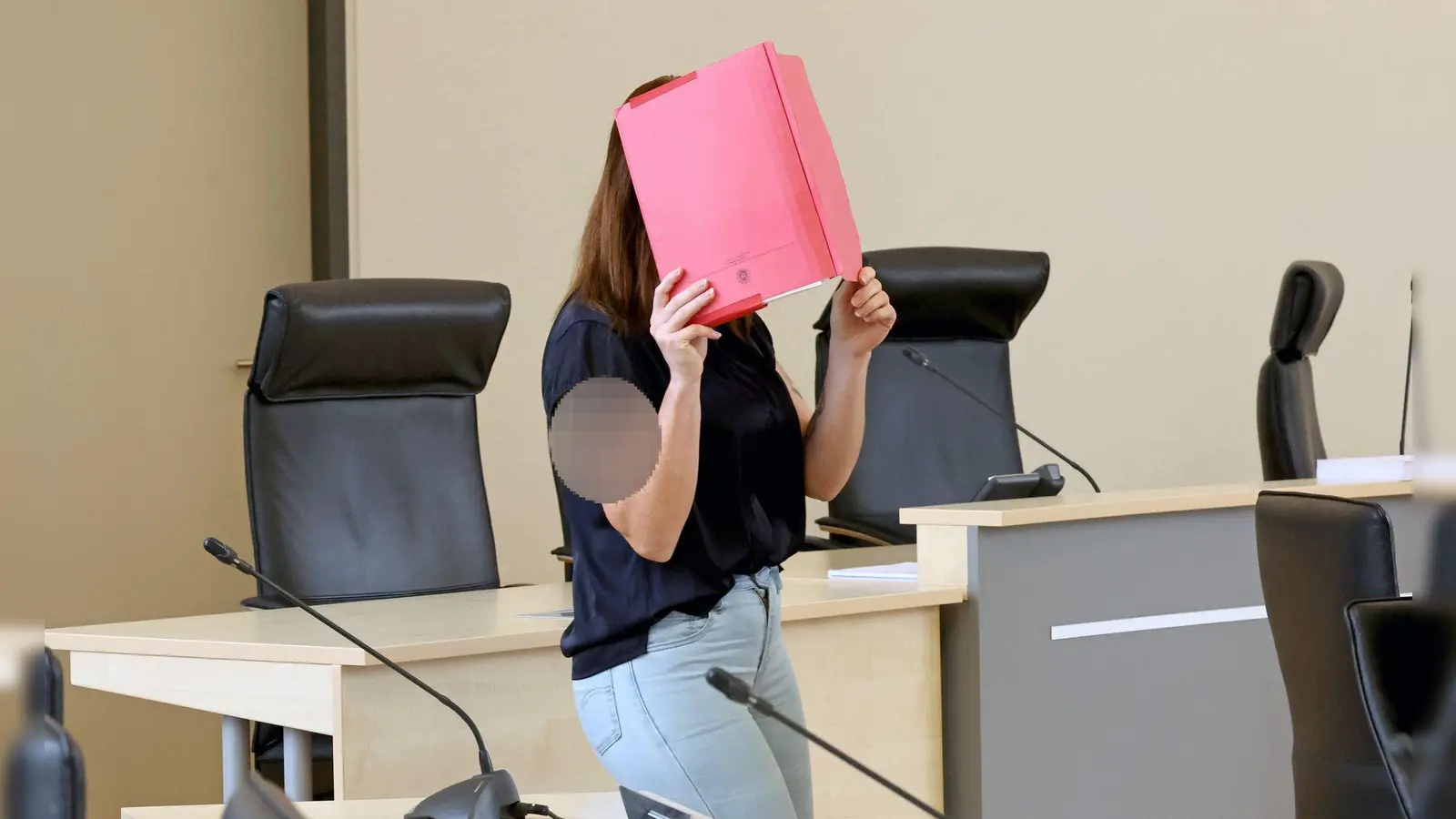 Die Angeklagte betritt den Gerichtssaal mit rotem Aktendeckel vor dem Gesicht. (Foto: A7120 Bernd Wüstneck/dpa)