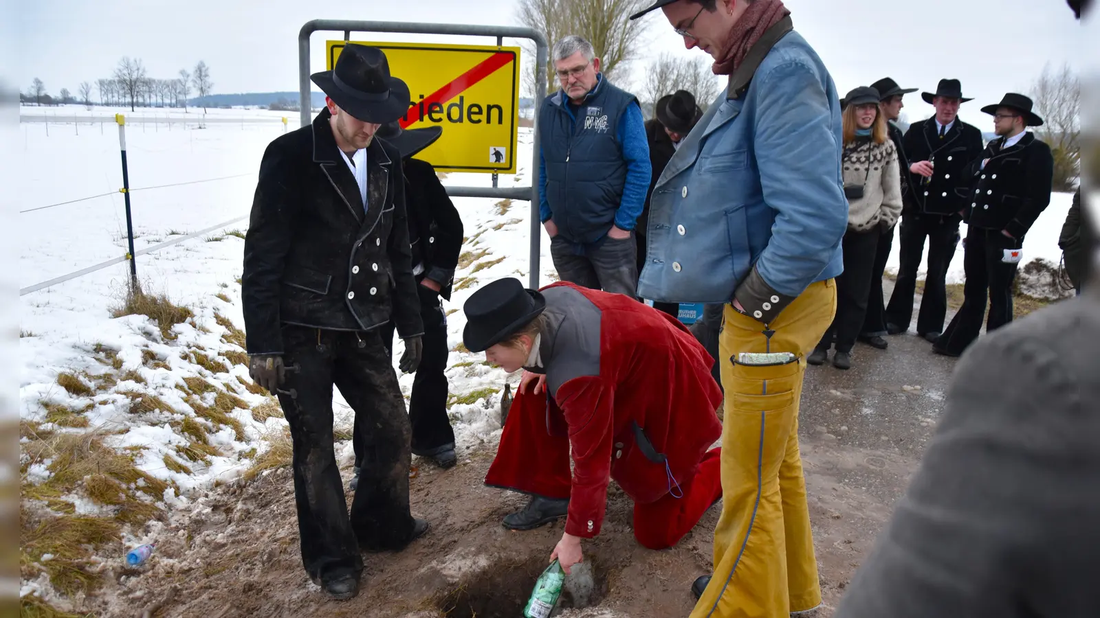 Begleiterin Fiona legte die Flaschen in das ausgebuddelte Loch, die Tim Oberfichtner (links) bei seiner Rückkehr nach mindestens drei Jahren wieder ausgraben und die halbe Flasche Schnaps als Dank für die erfolgreiche Walz mit Freunden austrinken wird. (Foto: Werner Wenk)