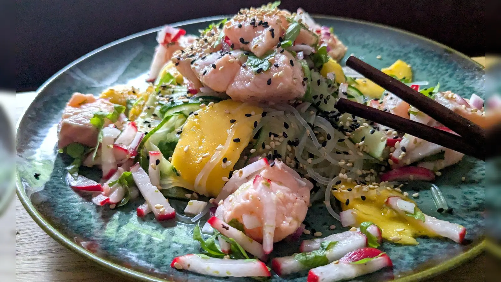 Der Glasnudelsalat mit Lachs-Ceviche wird mit gerösteten weißen und schwarzen Sesamkörnchen getoppt.  (Foto: Doreen hassek/hauptstadtkueche.blogspot.com/dpa-tmn)