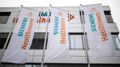 Das Logo und die Schriftzüge von Siemens Healthineers stehen auf Fahnen vor der Unternehmenszentrale. (Foto: Daniel Karmann/dpa/Archivbild)