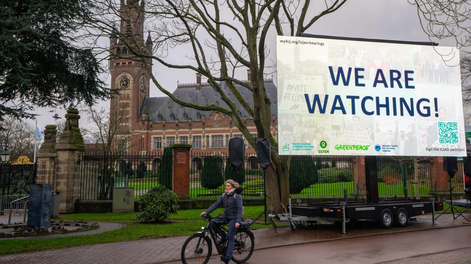 „We are Watching!“ ist auf einem Plakat vor dem Internationalen Gerichtshof zu lesen: Das höchste UN-Gericht hat sich mit Klimaschutz befasst. (Archivbild) (Foto: Peter Dejong/AP/dpa)