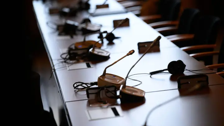 Mikrofone und Kopfhörer auf einem Tisch in einem Gerichtssaal. (Foto: Jonas Walzberg/dpa/Symbolbild)