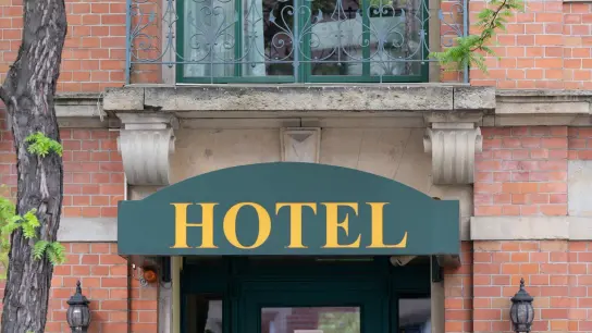 Ein Schild mit der Aufschrift „Hotel“ hängt an einem Hauseingang. (Foto: Sebastian Kahnert/dpa)