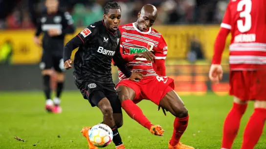 Jeremie Frimpong von Bayer Leverkusen (l) und Kelvin Yeboah vom FC Augsburg im Zweikampf um den Ball. (Foto: Matthias Balk/dpa/Archivbild)