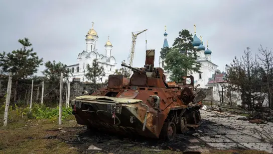 Ein zerstörter russischer Schützenpanzer steht vor einer Kirche in Isjum. (Foto: Evgeniy Maloletka/AP/dpa)