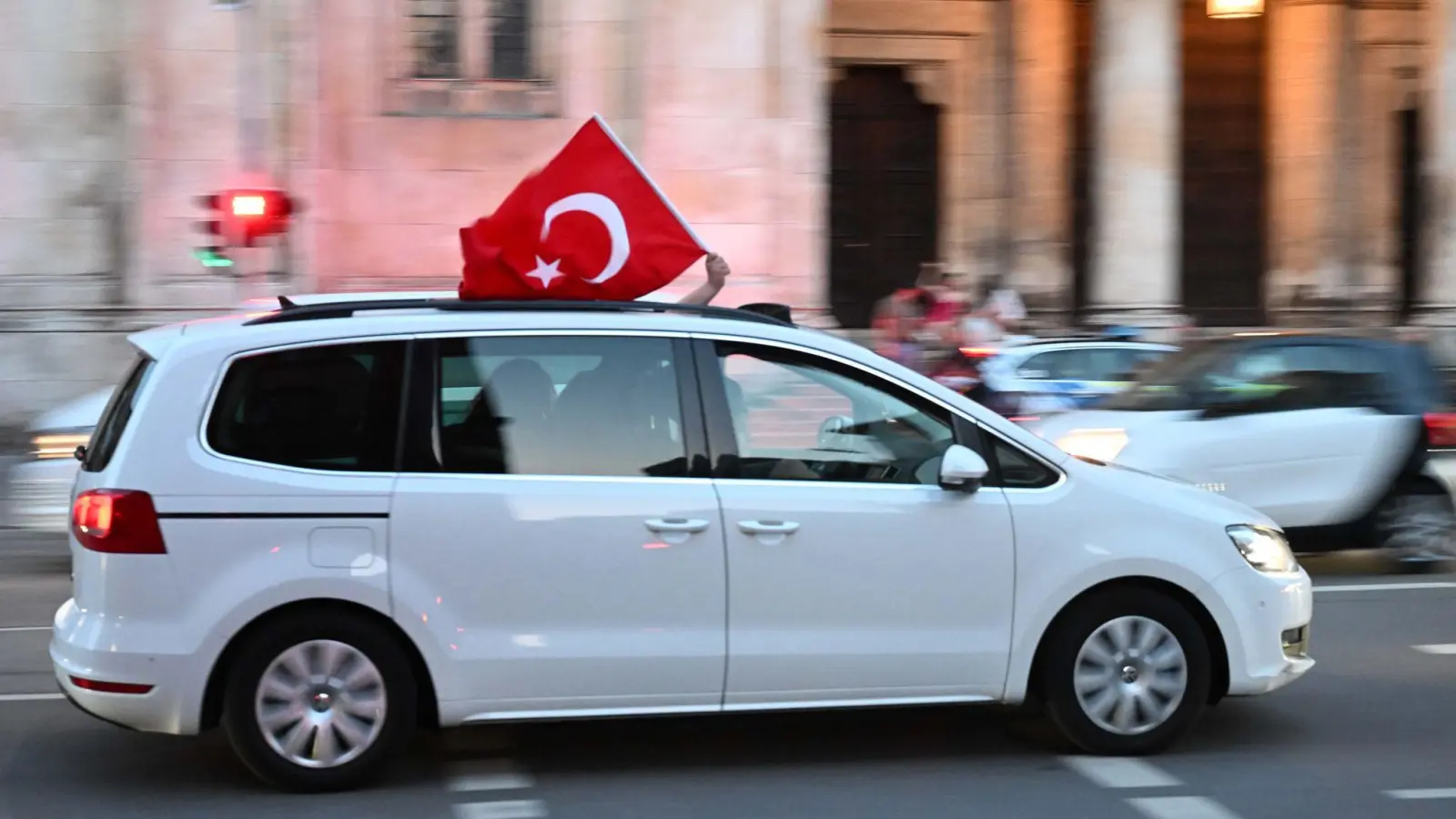 Ein Auto mit einer türkischen Flagge fährt über die Ludwigstraße, um den Ausgang der Wahl in der Türkei zu feiern. (Foto: Felix Hörhager/dpa)