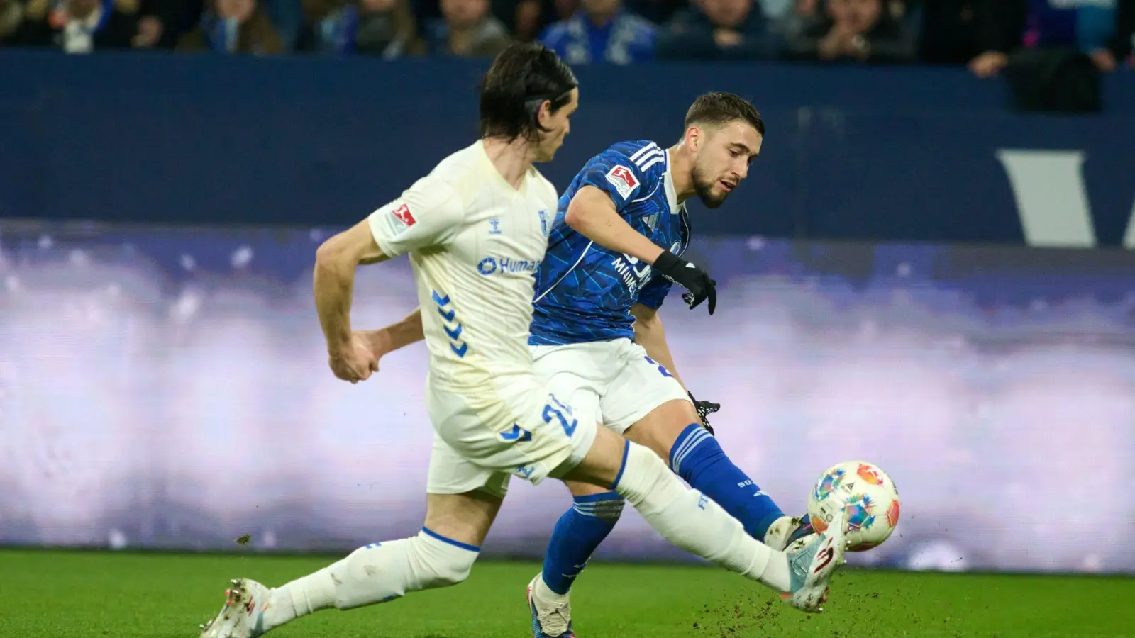 Das 1:0 für Schalke: Adil Aouchiche schießt, Magdeburgs Jean Hugonet fälscht mit der Fußspitze ab - und der Ball fliegt im hohen Bogen ins Tor.  (Foto: Bernd Thissen/dpa)