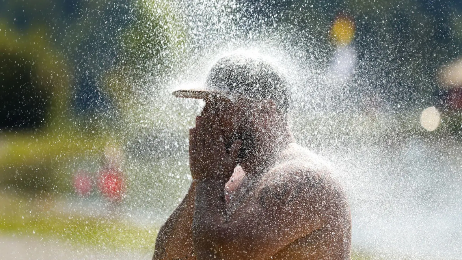 Ein Mann erfrischt sich an einem Badesee unter einer kalten Dusche. (Foto: Thomas Warnack/dpa)