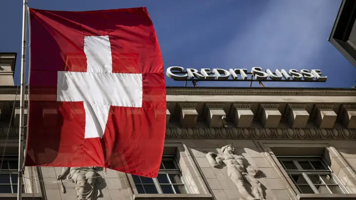 „Alle haben Angst vor dem Kollaps“: Die Flagge der Schweiz weht neben dem Logo der Schweizer Bank Credit Suisse in Luzern. (Foto: Michael Buholzer/KEYSTONE/dpa)