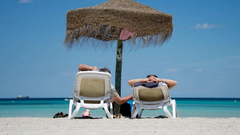 Entspannt am Strand: Wer sich vorher kurz mit möglichen Gesundheitsrisiken auseinandersetzt, ist im Urlaub relaxter. Sonnencreme nicht vergessen! (Foto: Julian Stratenschulte/dpa/dpa-tmn)