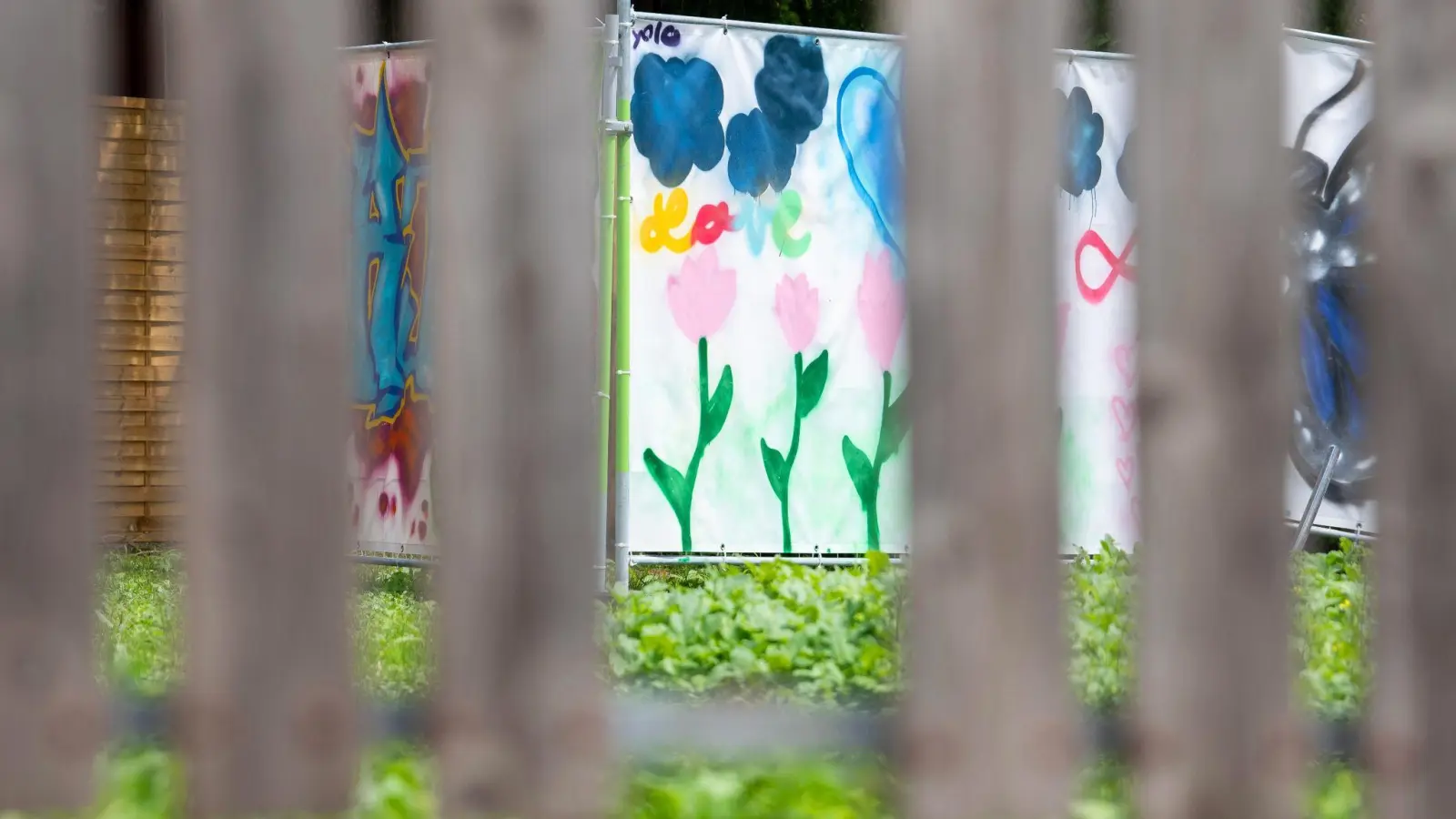 Am Rand einer Brachfläche hängen von Kindern gestaltete Plakate an Bauzäunen. An dieser Stelle stand das Haus, vor dem der Messerangriff auf zwei Schülerinnen stattfand. (Foto: Stefan Puchner/dpa)