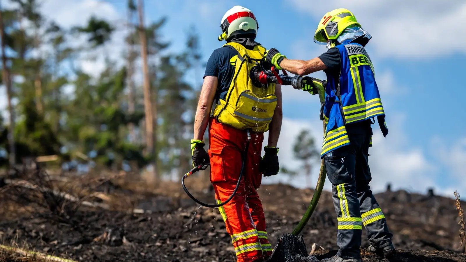 Mit Löschrucksäcken gehen die Feuerwehrleute etwa gegen Glutnester vor.  (Foto: Jacob Schröter/dpa)