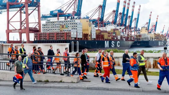 Hafenarbeiter gehen in Hamburg zu einer Streikversammlung. (Foto: Markus Scholz/dpa)
