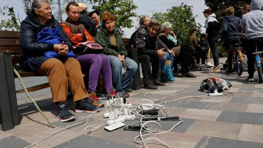 Menschen in Mariupol laden ihre Telefone auf - das Gebiet in der Ostukraine steht unter der Regierung der sogenannten Donezker Volksrepublik. (Foto: Alexei Alexandrov/AP/dpa)
