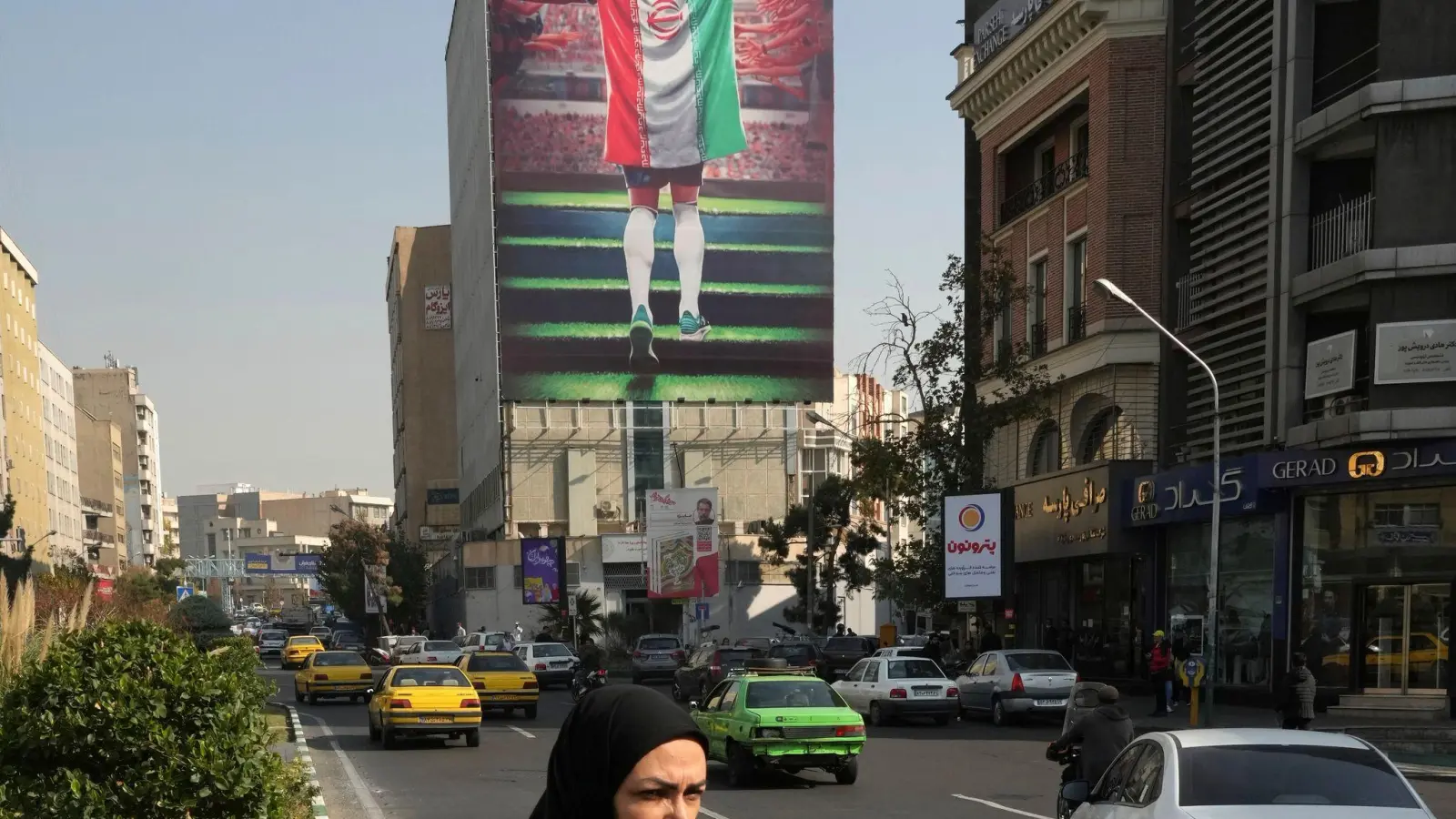 Ein Plakat zeigt einen Fußballspieler mit der Nationalflagge an einem Gebäude in Teheran. (Foto: Vahid Salemi/AP/dpa)