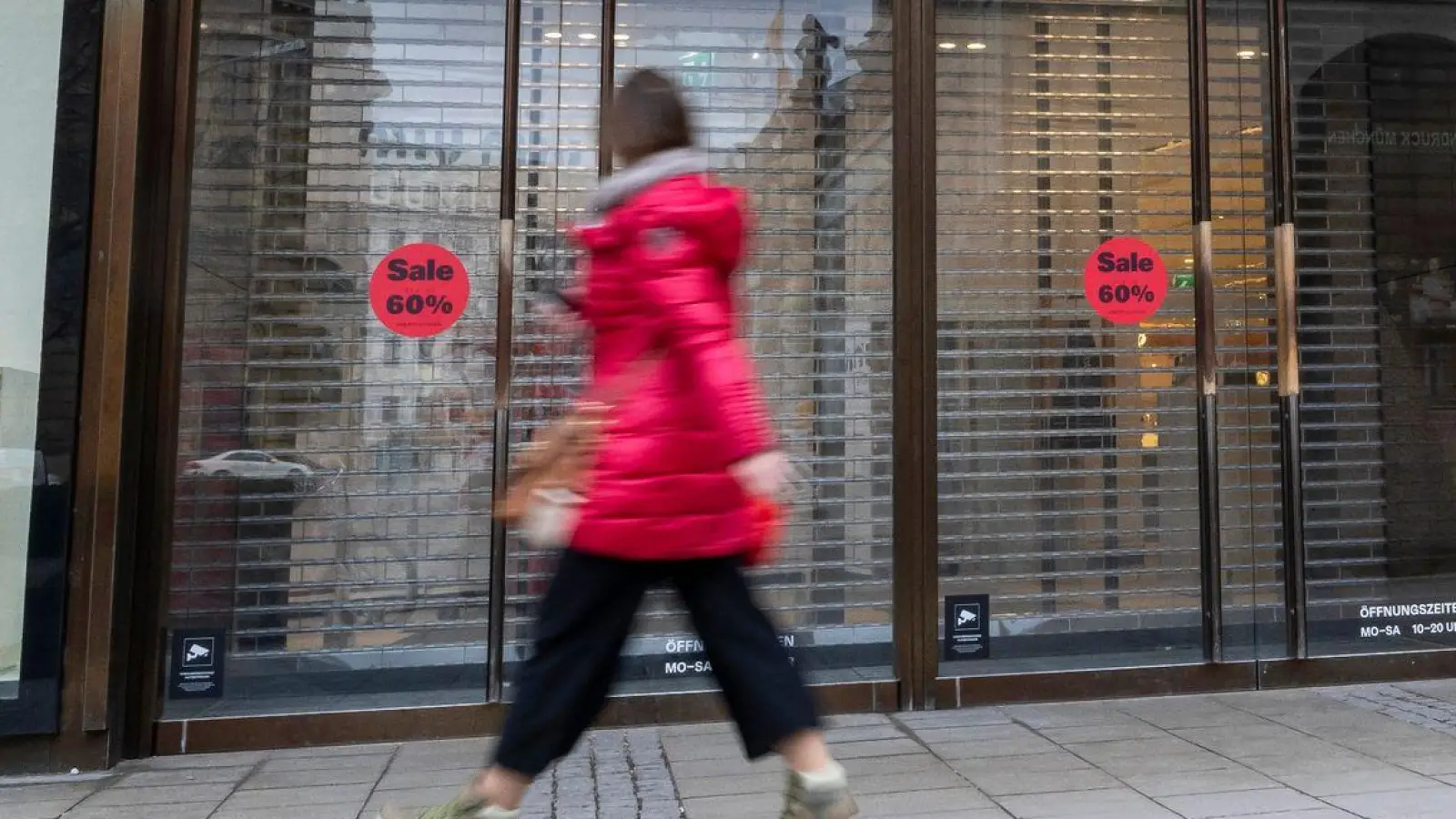 Eine Frau läuft vor Geschäftsöffnung an einem Eingang zum Kaufhaus Oberpollinger in München vorbei. (Foto: Peter Kneffel/dpa)
