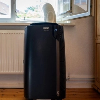 Monoblock-Klimagerät mit Abluftschlauch: Wer das Fenster abdichtet – wie hier mit einer Acrylglasscheibe mit Loch – spart Strom und kühlt effizienter. (Foto: Nico Tapia/dpa-tmn)