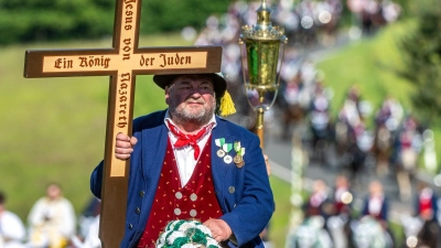 Ein Teilnehmer des Kötztinger Pfingstritts trägt ein Kreuz mit der Aufschrift „Jesus von Nazareth - Ein König der Juden“. (Foto: Armin Weigel/dpa)
