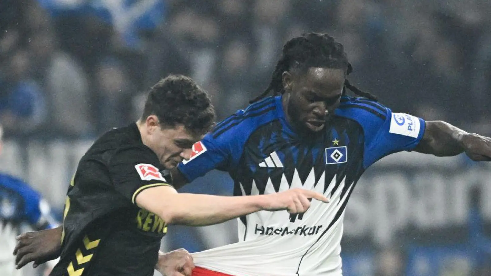 Kölns Eric Martel (l-r) und HSV-Abwehrspieler Jordan Torunarigha kämpfen um den Ball. (Foto: Gregor Fischer/dpa)