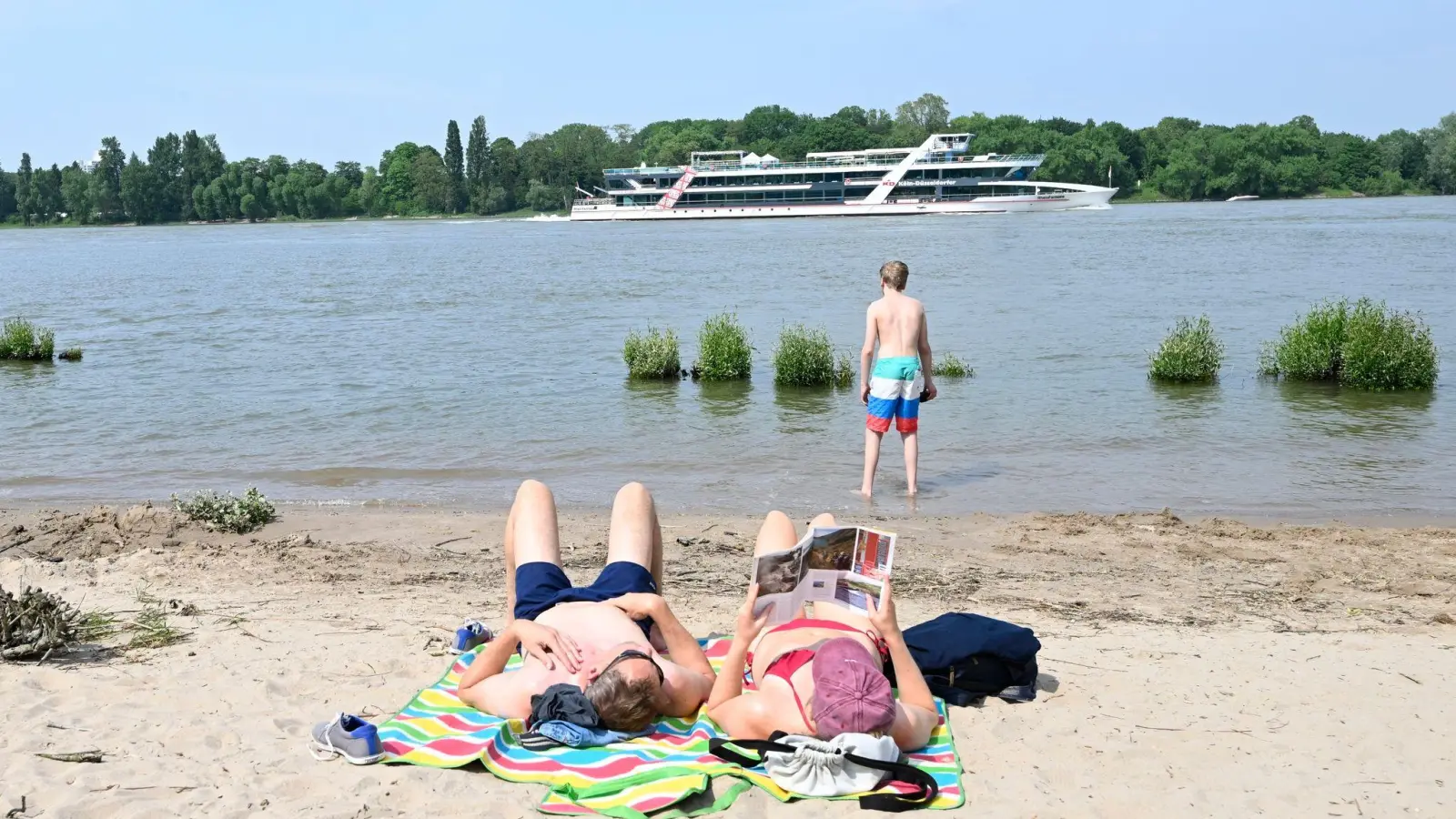 Eine Frau und ein Mann genießen am Rheinstrand die milden Temperaturen und die Sonne. (Foto: Roberto Pfeil/dpa)