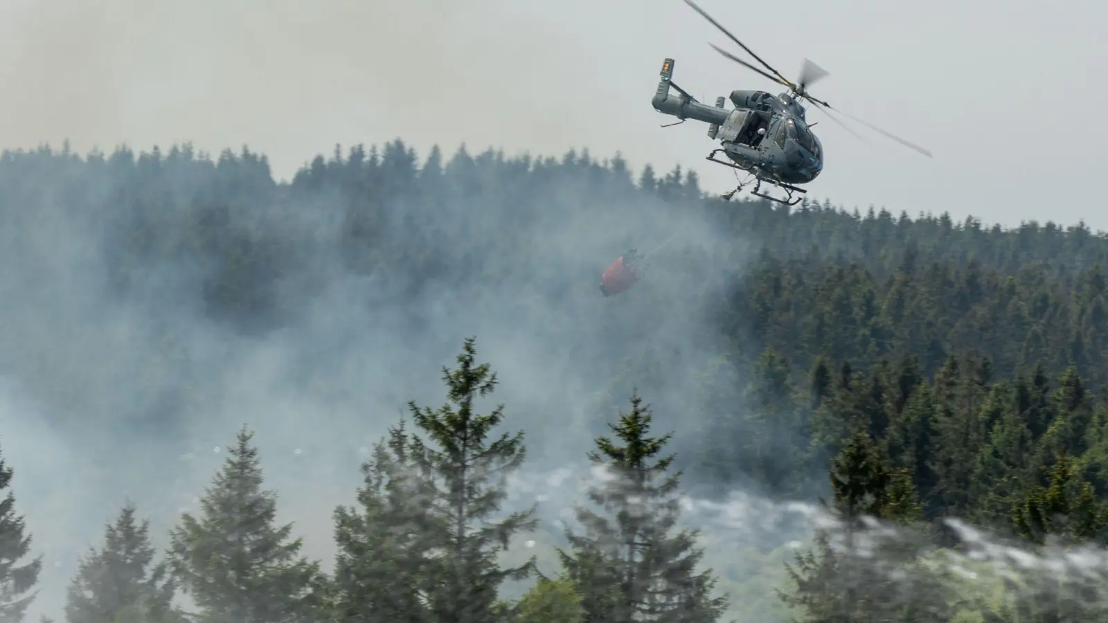Die Feuerwehr versucht mit einem Hubschrauber einen Moorbrand im deutsch-belgischen Grenzgebiet bei Aachen zu löschen. (Foto: Ralf Roeger/dmp-press/dpa)