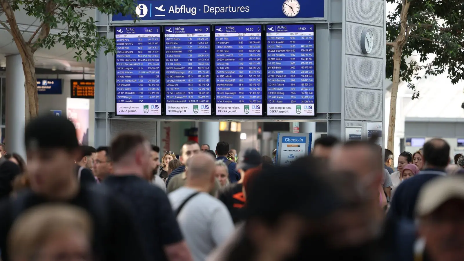 Reisende gehen durch den Flughafen Düsseldorf. Der Ferienstart im bevölkerungsreichsten Bundesland Nordrhein-Westfalen dürfte am Wochenende zu stundenlangen Wartezeiten führen. (Foto: David Young/dpa)