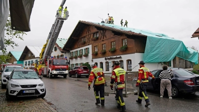 Arbeiter und Feuerwehrleute beseitigen die Unwetter-Schäden im oberbayerischen Bad Bayersoien. Bei dem Unwetter wurden viele Dächer beschädigt. (Foto: Uwe Lein/dpa)