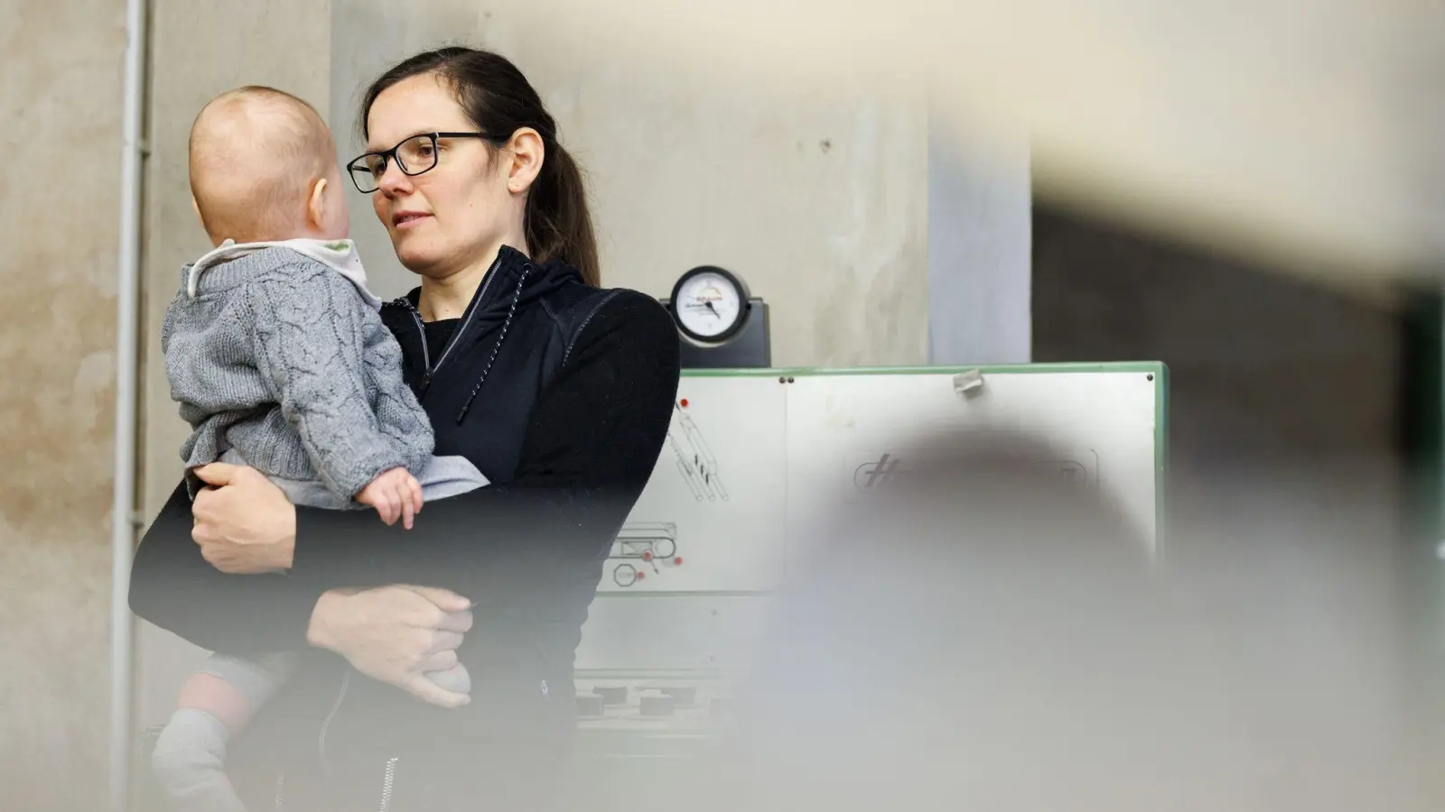 Tischlermeisterin Johanna Röh mit ihrem Kind in der Werkstatt ihres Betriebes. (Foto: Friso Gentsch/dpa)