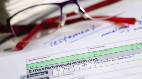 Ein Formular für die Erbschaftsteuererklärung sowie Brille und Testament liegen auf einem Tisch. (Foto: Hans-Jürgen Wiedl/dpa-Zentralbild/dpa/Symbolbild)