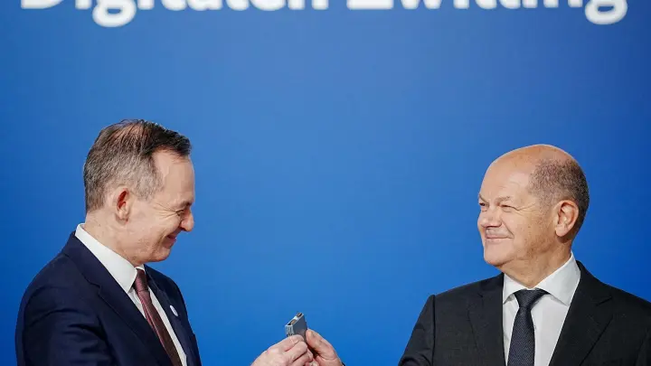 Bundeskanzler Olaf Scholz (r, SPD) übergibt an Volker Wissing (FDP), Bundesminister für Verkehr und Digitales, eine Komponente eines Schaltschranks weiter. (Foto: Kay Nietfeld/dpa)