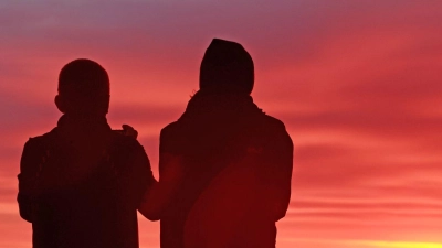 Der frühe Vogel... kann den Sonnenaufgang genießen. Zwei Wanderer stehen am frühen Morgen auf dem Brockengipfel. Heute soll es in Deutschland mit Temperaturen von bis zu 26 Grad sommerlich warm werden. (Foto: Matthias Bein/dpa)