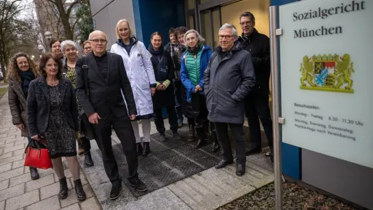 Der Augenarzt Gernot Petzold (vorne, 2.v.l) und einige Mitstreiter stehen vor Prozessbeginn vor dem Sozialgericht. (Foto: Peter Kneffel/dpa)
