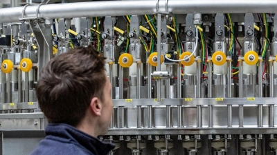 Ein Mitarbeiter der Krones AG arbeitet in der Produktion an einer Abfüllanlage. (Foto: Armin Weigel/dpa)