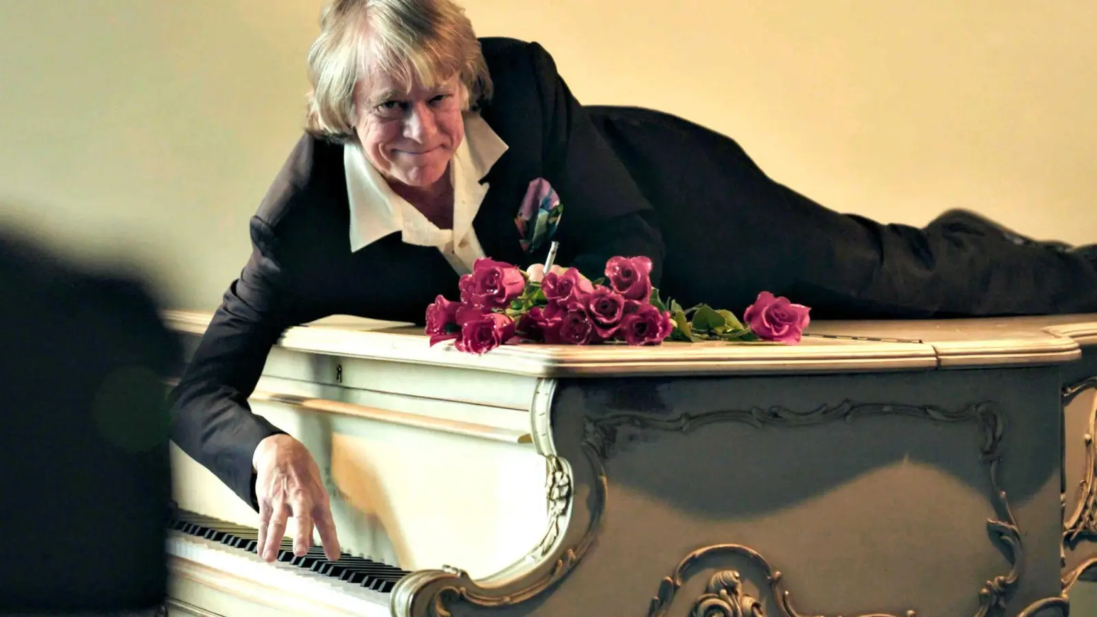 Helge Schneider liegt auf einem Klavier in einer Szene des Films „Helge Schneider - The Klimperclown“, der nun in der Mediathek zu sehen ist und am Mittwoch, 20.8., im Ersten gezeigt wird. (Foto: -/SWR Presse/Bildkommunikation/dpa)