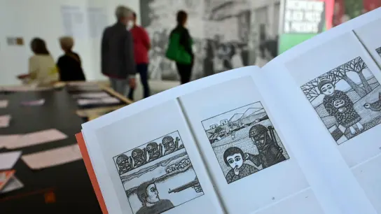 Eine Frau hält auf der documenta fifteen im Fridericianum die Broschüre mit dem Titel „Presence des Femmes“, die 1988 in Algier erschienen ist, in den Händen. Sie enthält weitere als antisemitisch kritisierte Motive. (Foto: Uwe Zucchi/dpa)
