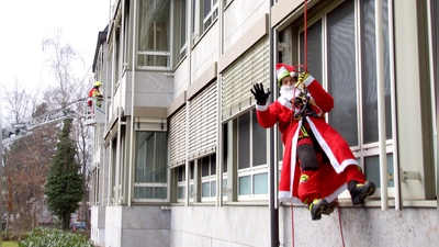 Höhenretter der Werksfeuerwehr Schaeffler seilten sich, als Nikoläuse verkleidet, von der Dachkante des Neustädter Krankenhauses ab. Auch die Neustädter Feuerwehr war „im Einsatz”. (Foto: Irene Wüchner)