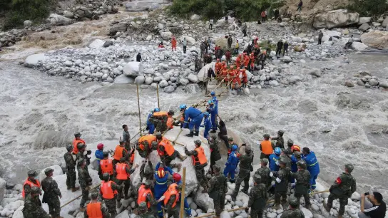 Rettungskräfte in der südwestchinesischen Stadt Moxi bauen eine Brücke, um Dorfbewohner nach dem Erdbeben über einen Fluss zu bringen. (Foto: Ye Xiaolong/Xinhua via AP/dpa)