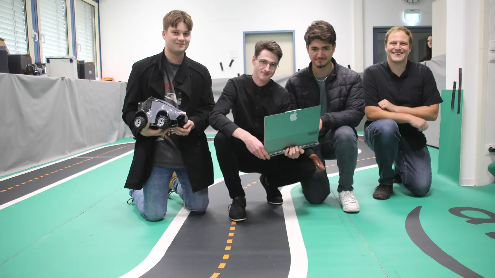 Christoph Guk, Lorenzo Rademacher und Berker Aydogdu (v.li.) sind drei der Teilnehmer am "Speed Racer"-Wettbewerb an der Hochschule Ansbach. Es galt, eine Künstliche Intelligenz im autonomen Fahren zu programmieren. Professor Dr. Stefan Geißelsöder ist sehr angetan, was die Studierenden in kürzester Zeit, umgesetzt haben. (Foto: Robert Maurer)