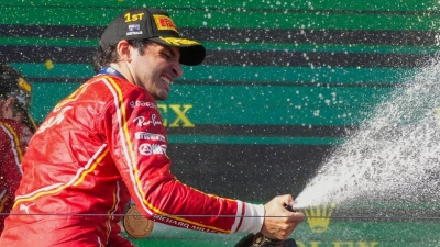 Ferrari-Pilot Carlos Sainz feiert mit Champagner seinen Sieg. (Foto: Scott Barbour/AP/dpa)