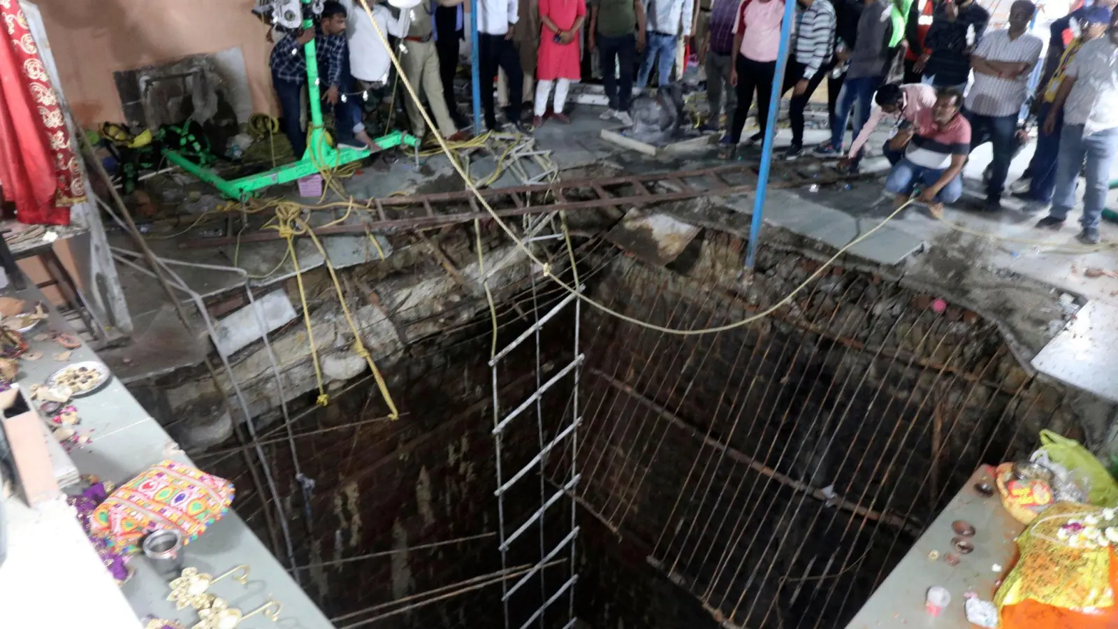 Menschen stehen an einem alten Brunnenbauwerk, über dem ein Tempel gebaut worden war, dessen Boden eingestürzt ist. (Foto: Uncredited/AP)