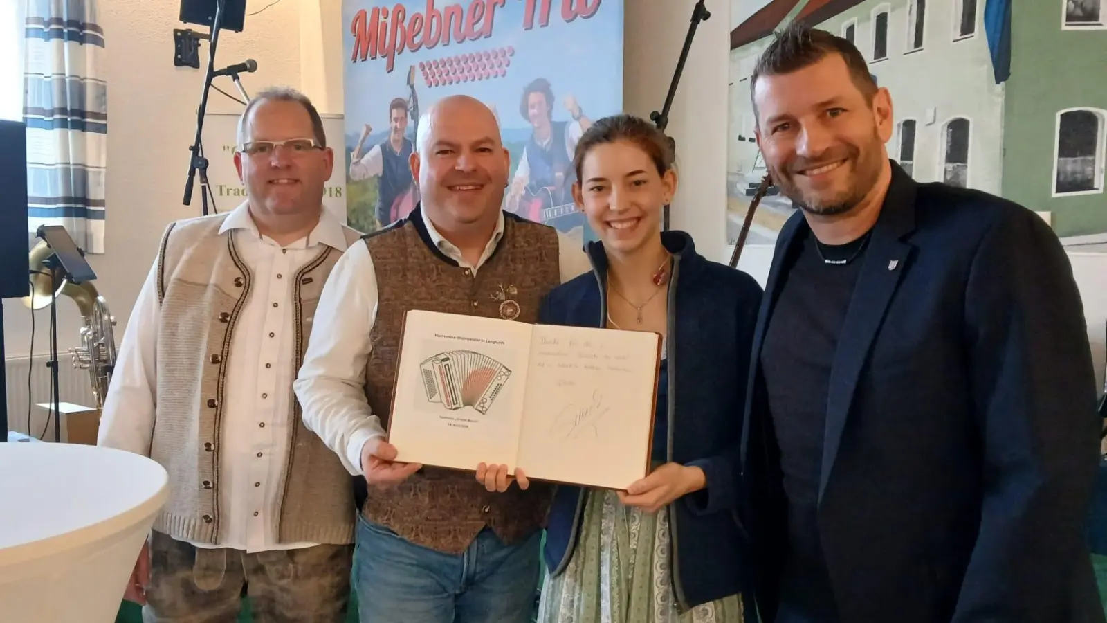 Gastwirt Bernd Engelhardt (links) und Bürgermeister Simon Schäffler (rechts) flankieren die Harmonika-Weltmeister Aleksander Pacek und Klara Mißebner nach deren Eintrag ins goldene Buch der Gemeinde Langfurth. (Foto: Friedrich Zinnecker)