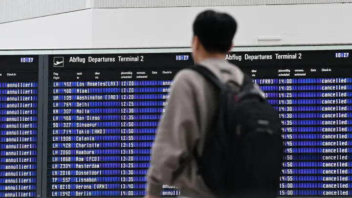 Ein Passagier steht im Münchner Flughafen vor der Anzeigentafel. (Foto: Angelika Warmuth/dpa)