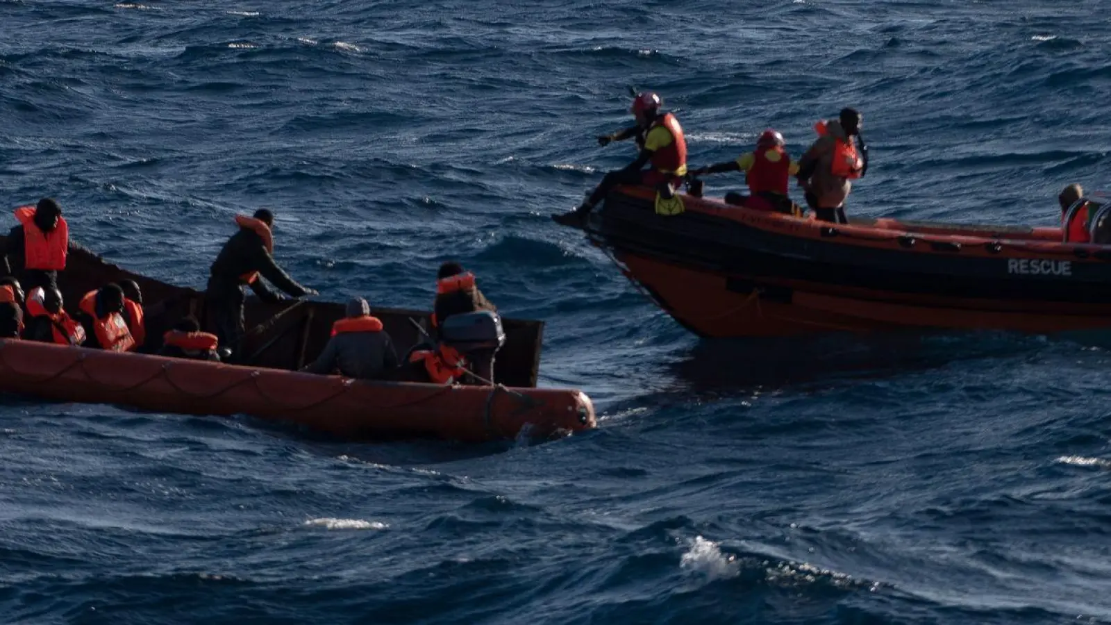 Migranten sitzen in einem Boot im Mittelmeer; Rettungskräfte versuchen, ihnen zu helfen. (Foto: Antonio Sempere/EUROPA PRESS/dpa)