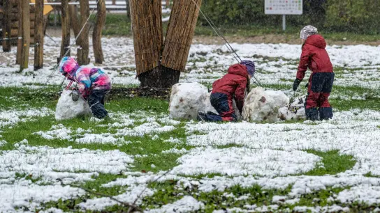 Kinder in Straubing versuchen, einen Schneemann zu bauen. (Foto: Armin Weigel/dpa)