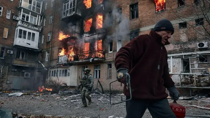 Ein Anwohner verlässt in Bachmut sein Wohnhaus, das nach einem Beschuss in Flammen steht. (Foto: Libkos/AP/dpa)