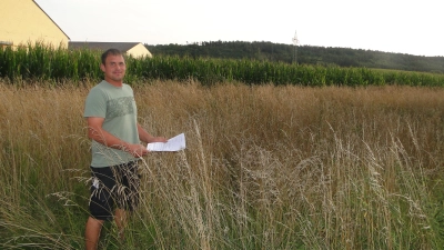 Bauherr Stefan Rauscher steht auf dem Grundstück, das er für den Bau zweier Mehrfamilienhäuser erwerben will. Für ihn ist der Maisacker eine Baulücke. In der Hand hält er den Vorbescheid des Landratsamtes. (Foto: Winfried Vennemann)